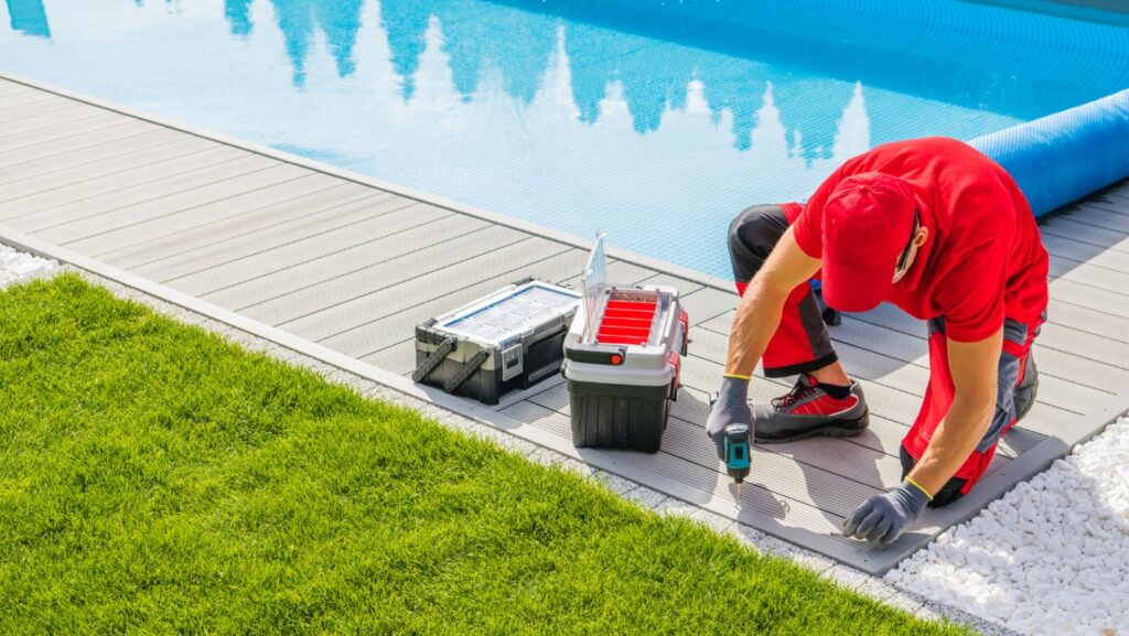 A builder uses tools to install the decking around a pool